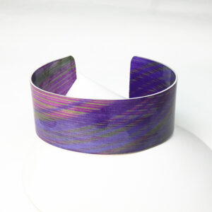 Brazalete en aluminio con franjas en morado, verde y rojo.