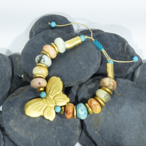 Pulsera artesanal con mariposa en oro mate, ópalos africanos, turquesas y hematites.